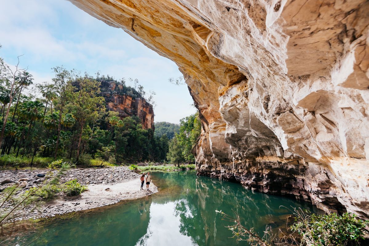 People standing next to waterhole near cliff